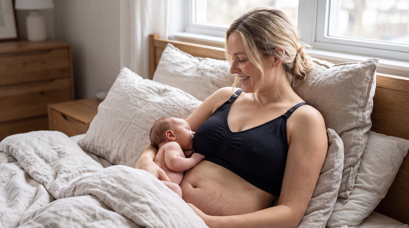A mother breastfeeding her newborn in a relaxed laid-back position in bed